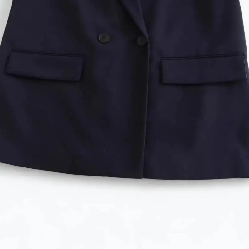 Close-up da parte inferior do blazer feminino azul-marinho, com botões e bolsos frontais com lapela.