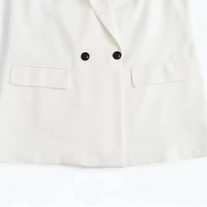 Close-up da parte inferior do blazer feminino branco, com botões e bolsos frontais com lapela.