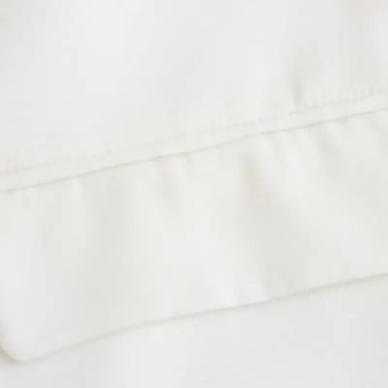 Close-up do bolso frontal com lapela do blazer feminino branco, destacando a costura e a textura do tecido.