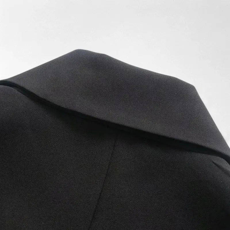 Close-up da gola e parte superior das costas do blazer feminino preto.