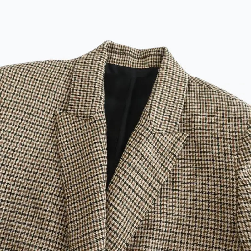 Close-up da gola e lapelas entalhadas do blazer feminino xadrez, destacando o padrão miúdo e o forro preto.