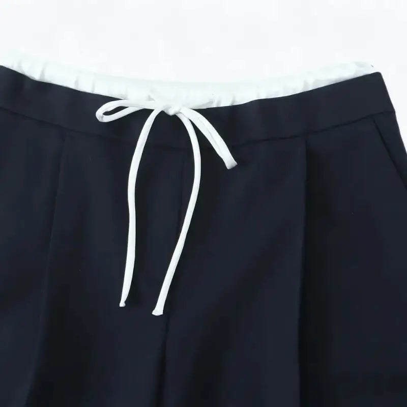 Close-up da cintura alta da calça alfaiataria feminina azul marinho, destacando o cordão de amarração branco.