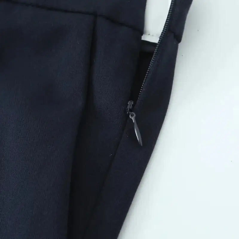 Close-up do zíper lateral invisível da calça alfaiataria feminina azul marinho.