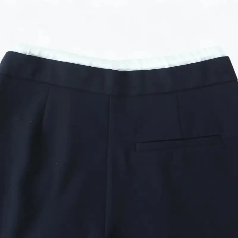 Close-up da cintura traseira da calça alfaiataria feminina azul marinho, com bolso falso embutido traseiro.