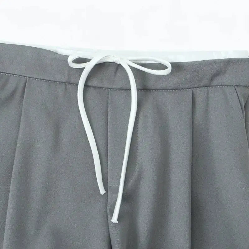 Close-up da cintura alta da calça alfaiataria feminina cinza, destacando o cordão de amarração branco.