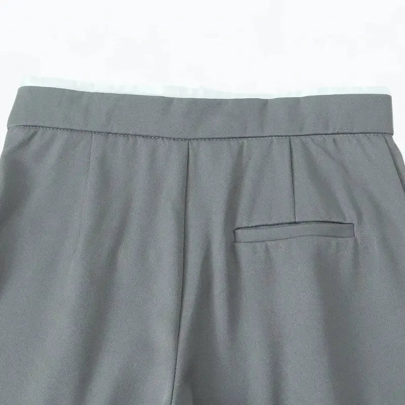 Close-up da cintura traseira da calça alfaiataria feminina cinza, com bolso falso embutido traseiro.