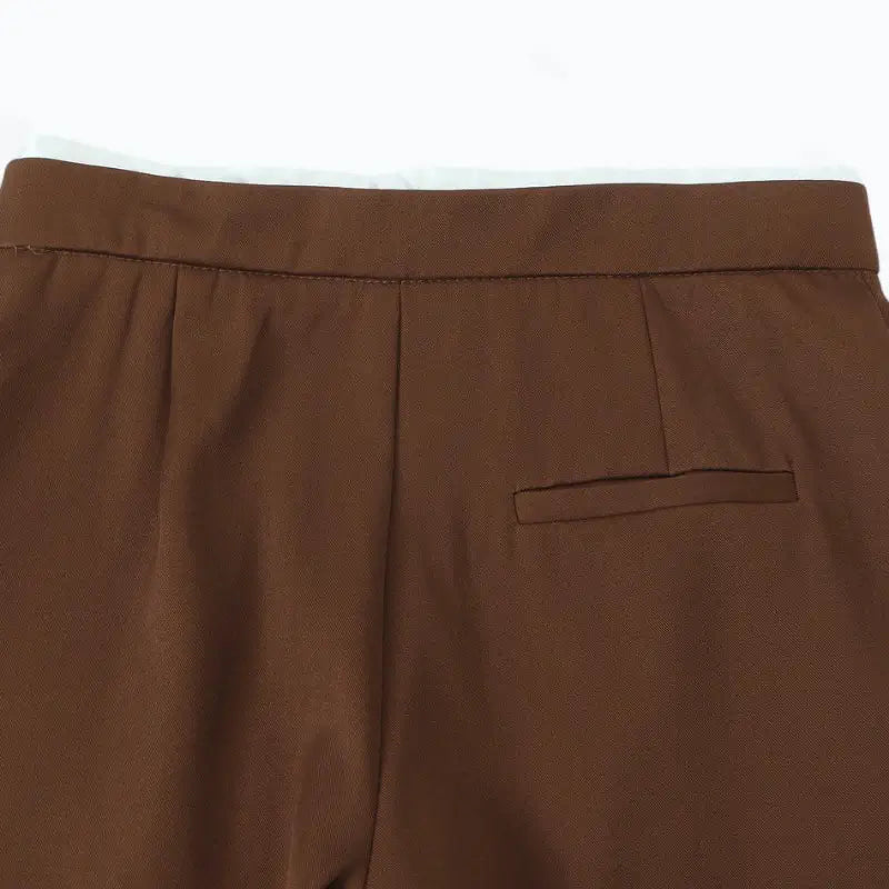 Close-up da cintura traseira da calça alfaiataria feminina marrom, com bolso falso embutido traseiro.