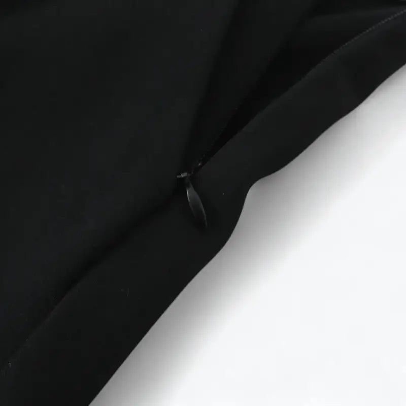 Close-up do zíper lateral invisível da calça alfaiataria feminina preta.