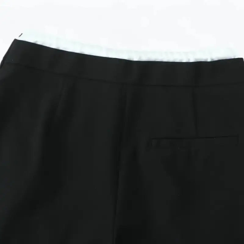 Close-up da cintura traseira da calça alfaiataria feminina preta, com bolso falso embutido traseiro.