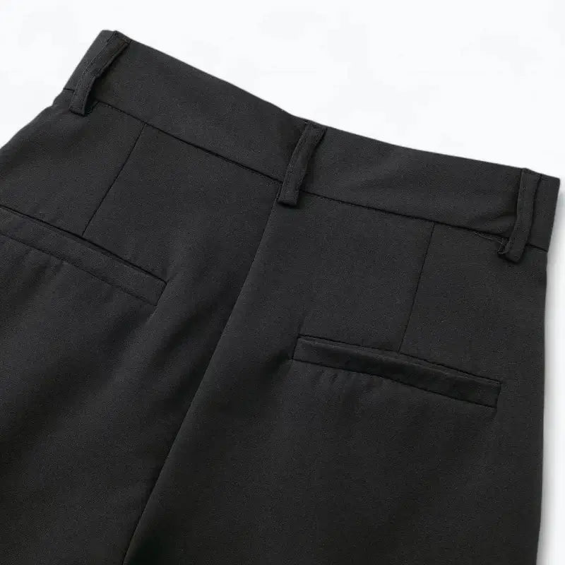 Close-up da cintura traseira da calça alfaiataria feminina preta, com presilhas de cinto e bolsos falsos embutidos.