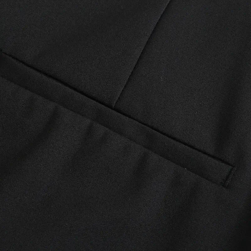 Close-up de um bolso falso embutido em calça feminina preta, detalhando a costura e o acabamento.