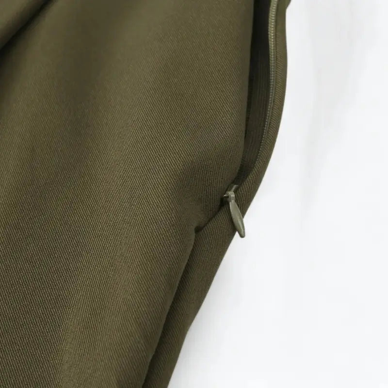 Close-up do zíper lateral invisível da calça alfaiataria feminina verde.