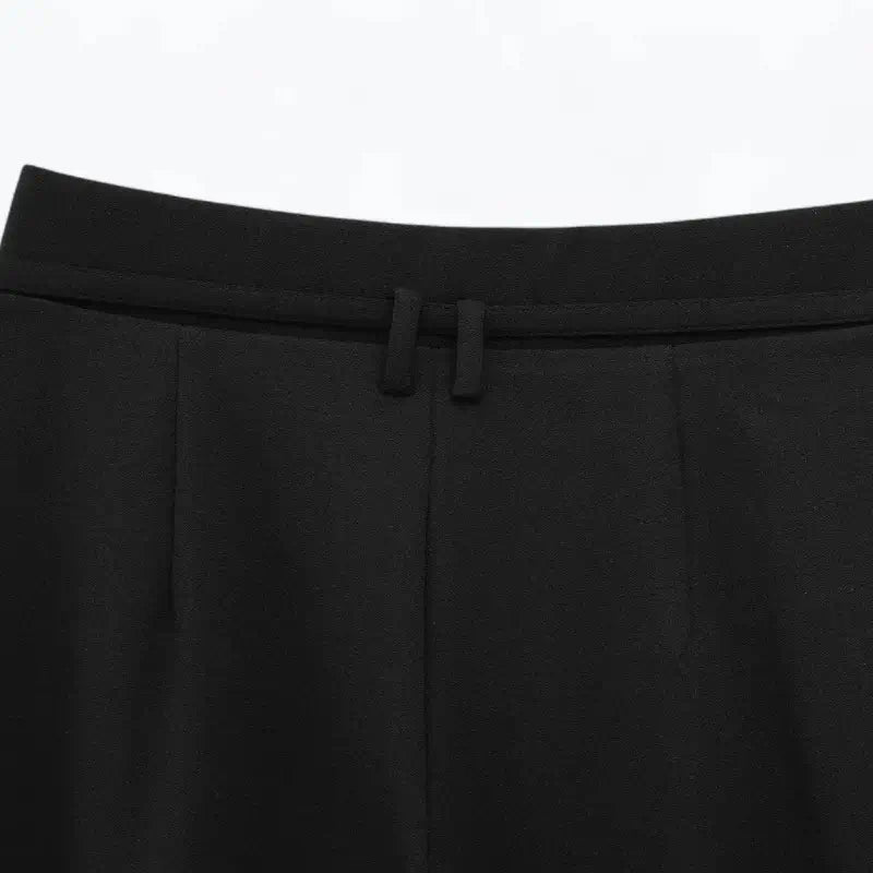 Close-up da parte traseira da cintura alta da calça feminina preta, detalhando o cinto fino e as presilhas.