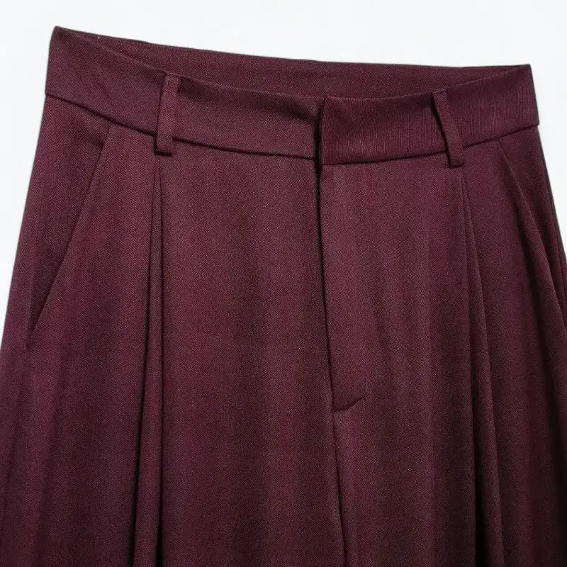 Close-up da cintura alta e pregas frontais da calça pantalona feminina vermelha, destacando as presilhas de cinto.