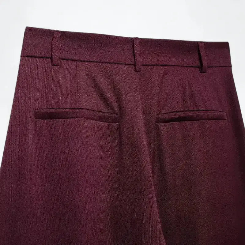 Close-up da cintura traseira da calça pantalona feminina vermelha, com presilhas de cinto e bolsos embutidos.
