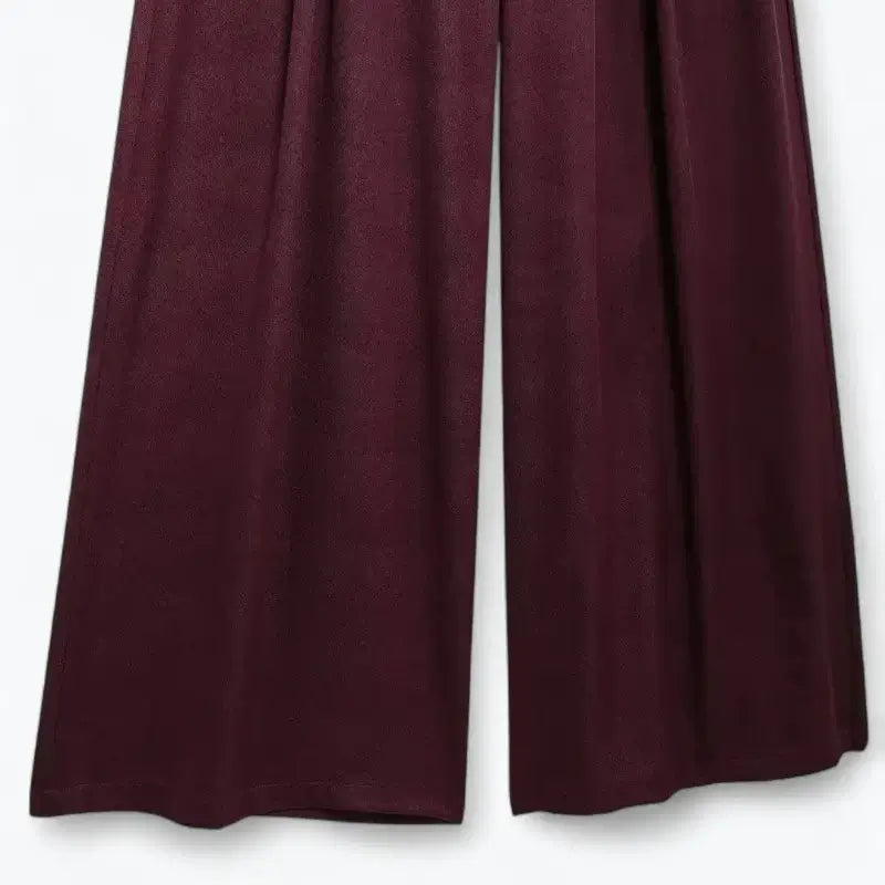 Close-up das pernas largas da calça pantalona feminina vermelha, mostrando o caimento fluido.