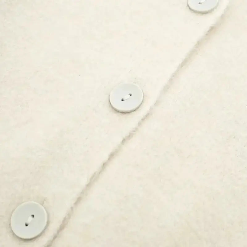 Close-up dos botões do cardigan feminino off white.