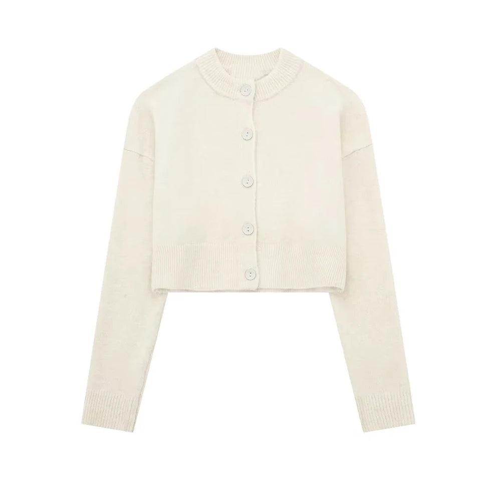 Cardigan feminino curto off white, com gola redonda canelada, mangas longas e botões frontais da mesma cor, exibido em fundo branco.