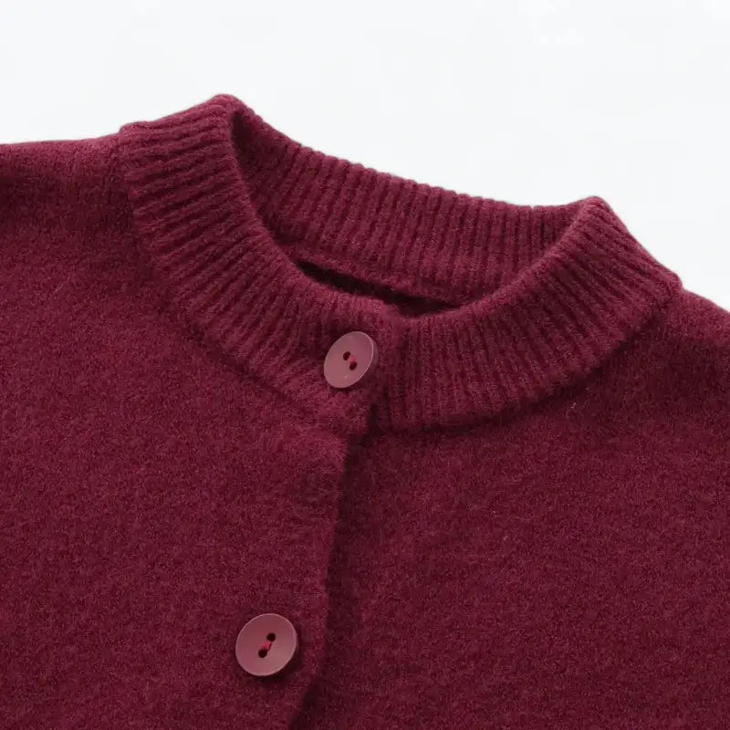 Close-up da gola redonda canelada e botões frontais do cardigan feminino vermelho, destacando a textura felpuda.