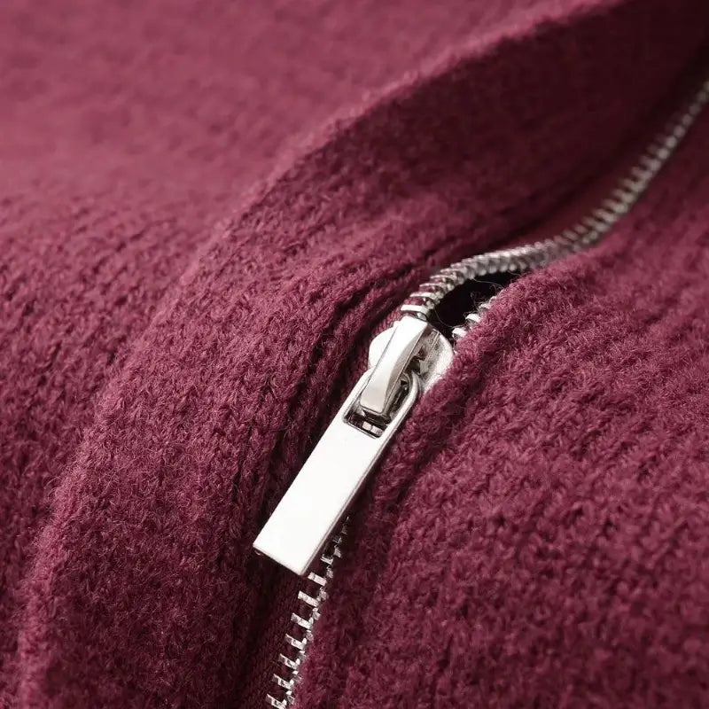 Close-up do zíper metálico prateado no cardigan feminino vermelho, destacando o puxador.