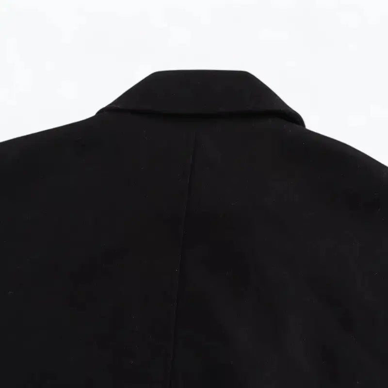 Close-up da gola e parte superior das costas do casaco feminino oversized preto, destacando a costura vertical central.