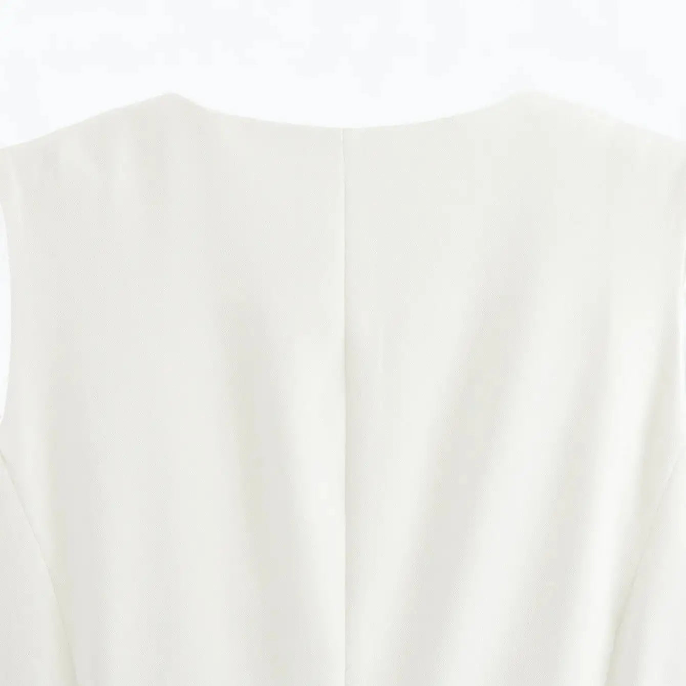 Close-up da parte traseira da gola arredondada e parte superior das costas do colete feminino alongado branco.