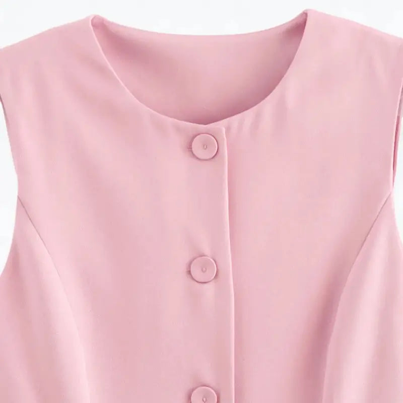 Close-up da gola redonda e botões frontais do colete feminino alongado rosa.