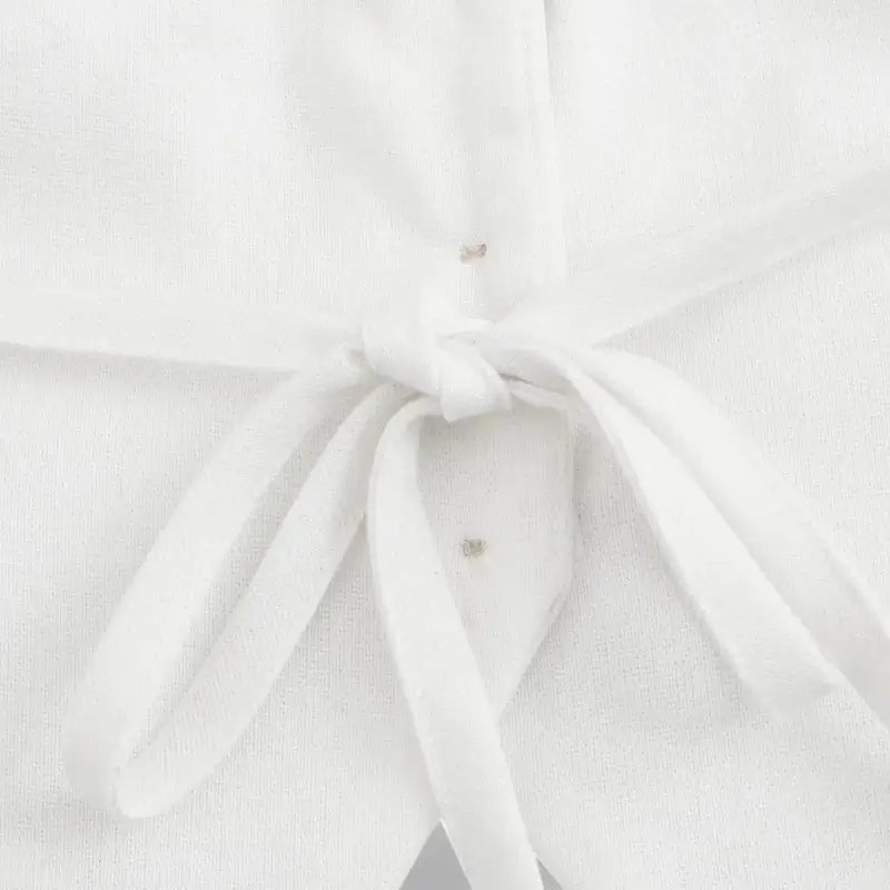 Close-up da parte traseira do colete feminino de alfaiataria branco, detalhando a tira ajustável amarrada em laço.