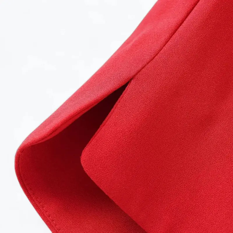 Close-up da fenda lateral e acabamento da barra do colete feminino de alfaiataria vermelho