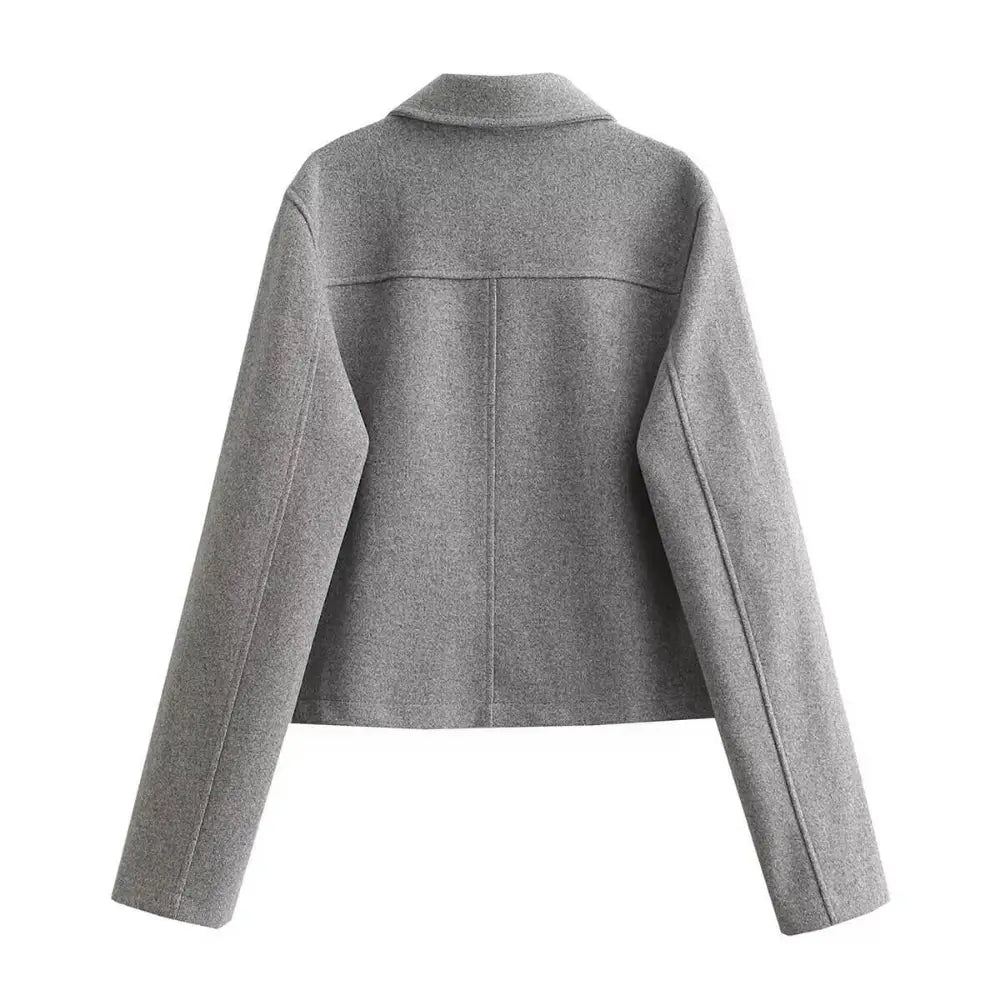 Vista traseira da jaqueta feminina de alfaiataria cinza, com gola e detalhes de costura horizontal nas costas, em fundo branco.