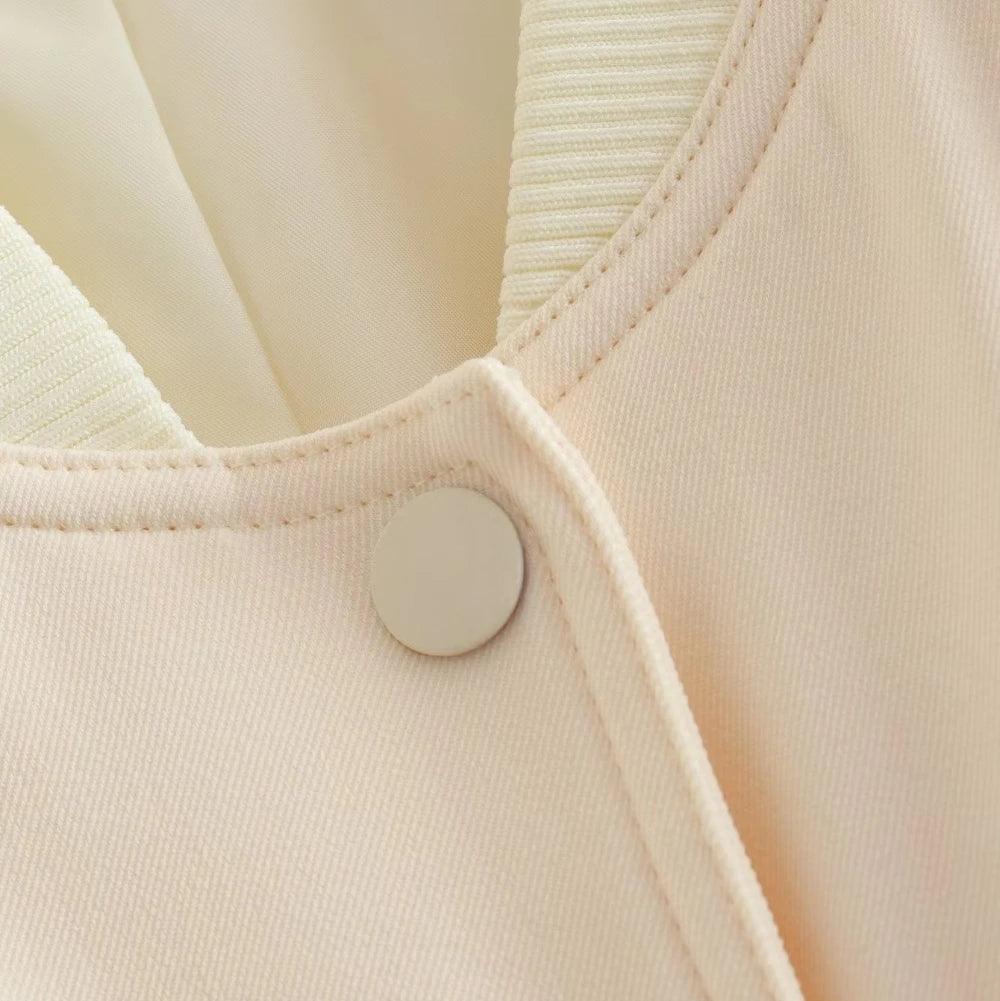 Close-up no decote da jaqueta bomber feminina off-white, destacando o botão de pressão redondo e a gola canelada.