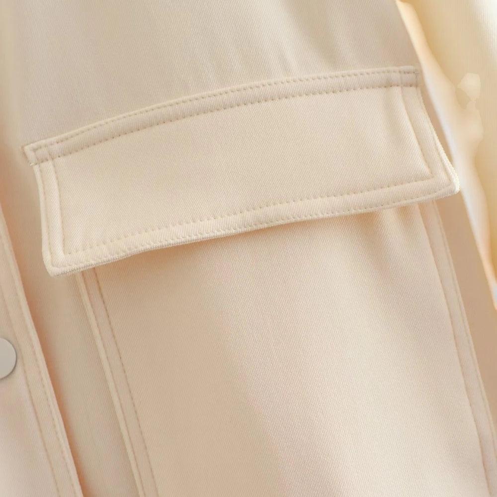 Close-up de um bolso frontal chapado com lapela da jaqueta bomber feminina off-white, detalhando a textura lisa do tecido.