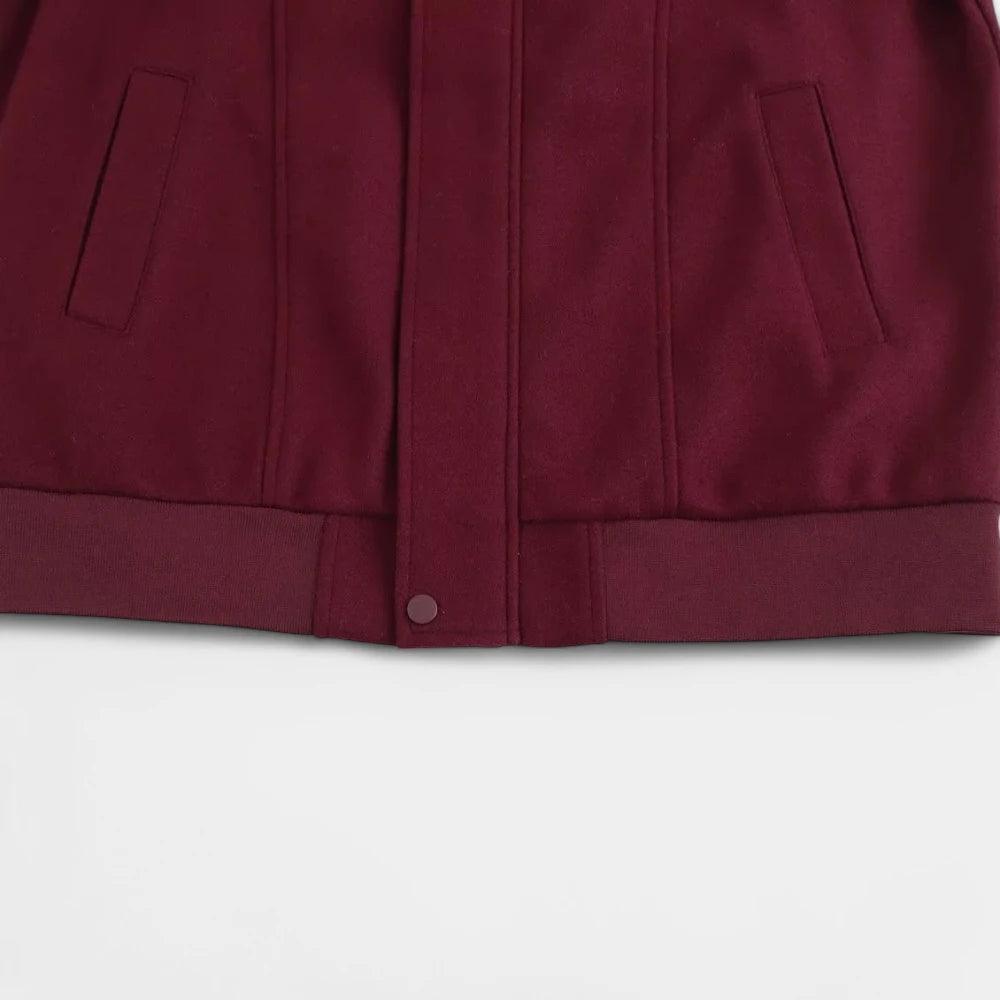 Close-up da barra canelada da jaqueta bomber feminina vermelha, com botão de pressão e bolsos embutidos.