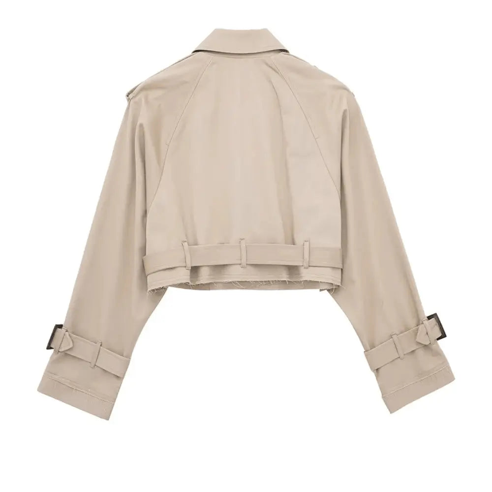 Vista traseira da jaqueta feminina cropped bege estilo trench coat, com cinto na barra, alças nos ombros e fivelas nos punhos, em fundo branco.