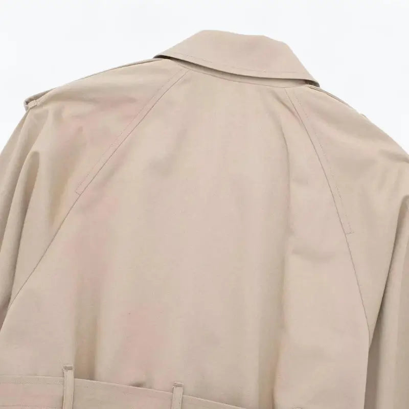 Close-up da parte superior das costas da jaqueta feminina cropped bege, mostrando a gola e as costuras estilo trench coat.