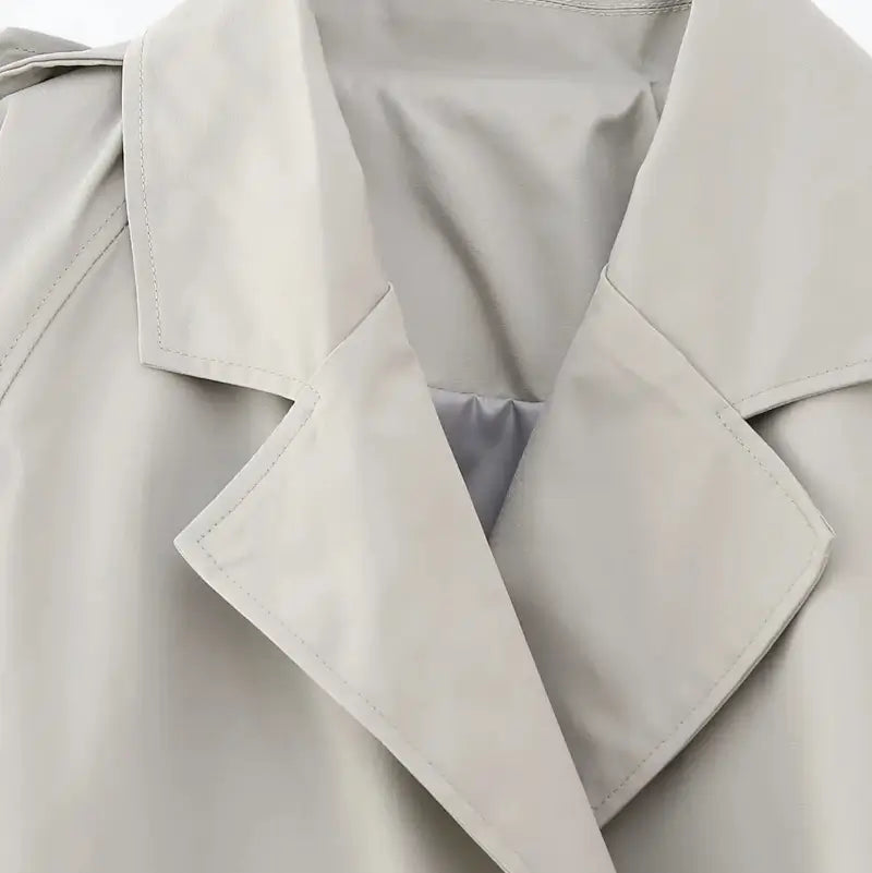 Close-up na gola da jaqueta feminina cropped cinza estilo trench coat.
