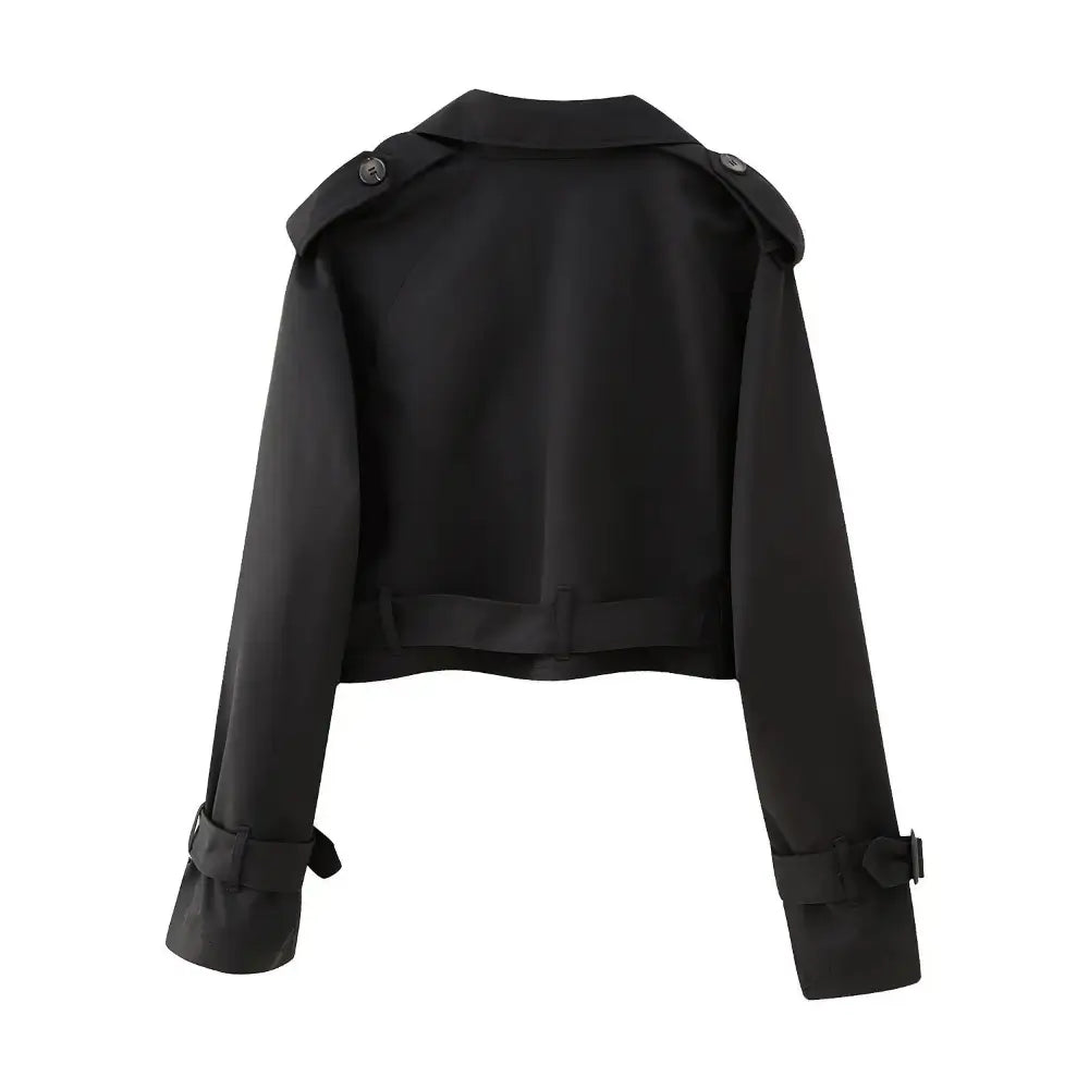 Vista traseira da jaqueta feminina cropped preta estilo trench coat, com cinto na barra, alças nos ombros e fivelas nos punhos, em fundo branco.