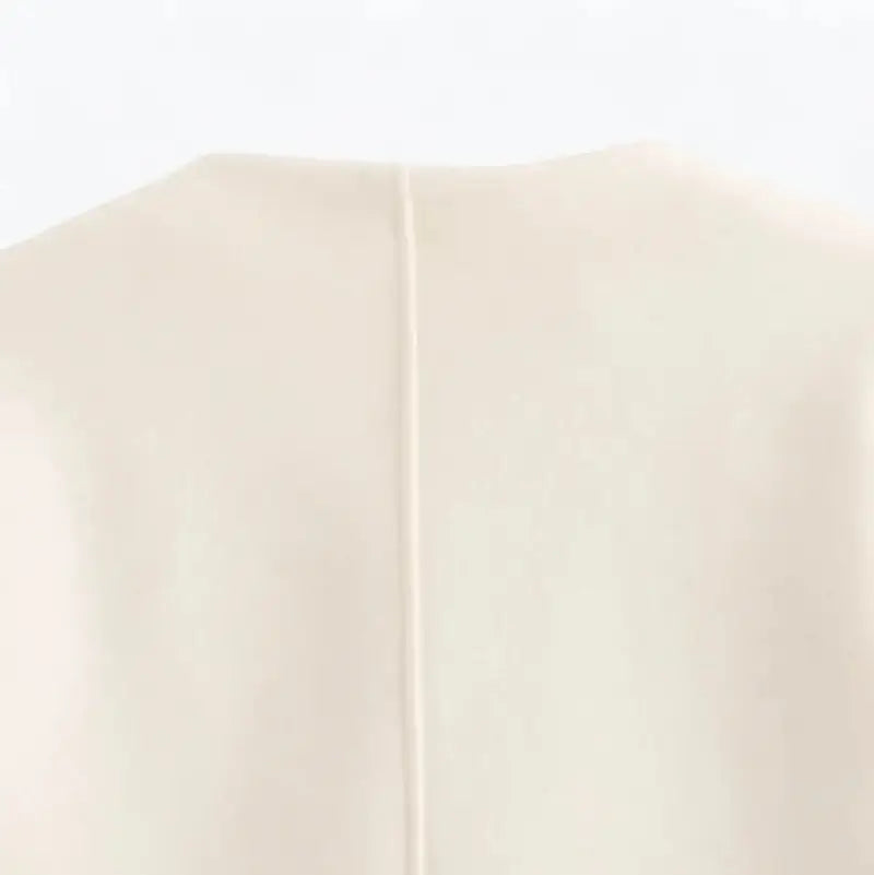 Close-up do decote traseiro da jaqueta feminina off-white, exibindo a costura vertical centralizada nas costas.