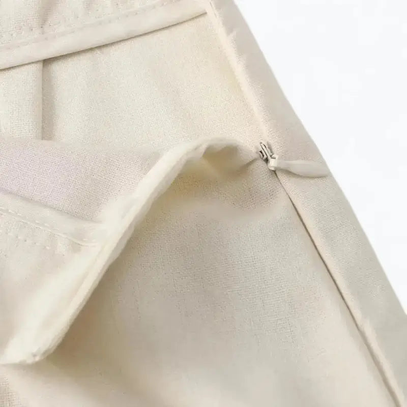 Close-up da lateral da saia longa midi de alfaiataria off white, detalhando o zíper invisível e o acabamento da cintura.