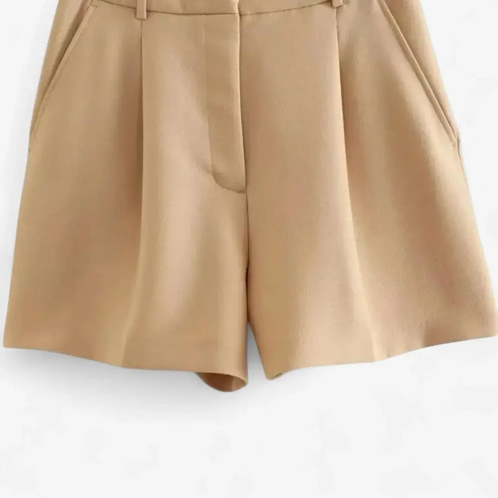 Short alfaiataria feminino bege, modelo cintura alta com pregas frontais bem marcadas e bolsos laterais discretos, exibido sobre fundo branco
