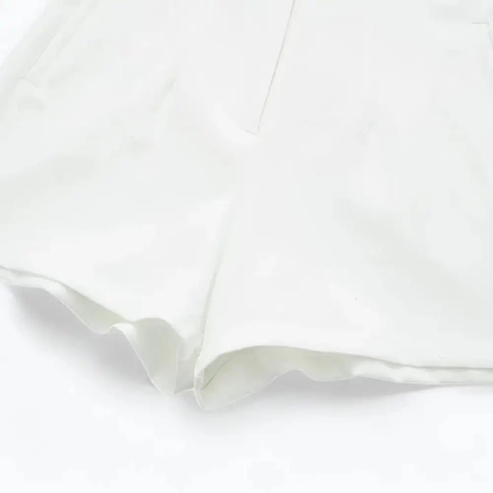 Close-up da barra do short feminino de alfaiataria branco, detalhando o acabamento e a costura da virilha.