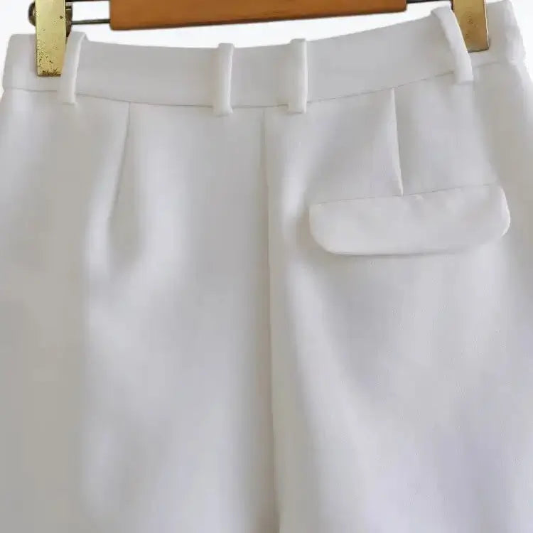 Vista traseira do short alfaiataria feminino branco, de cintura alta, com presilhas de cinto e detalhe de bolso com aba na parte posterior.