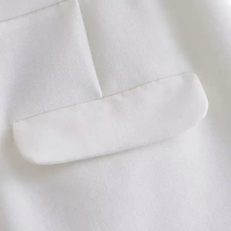 Close-up do bolso traseiro com aba, do short alfaiataria feminino branco.