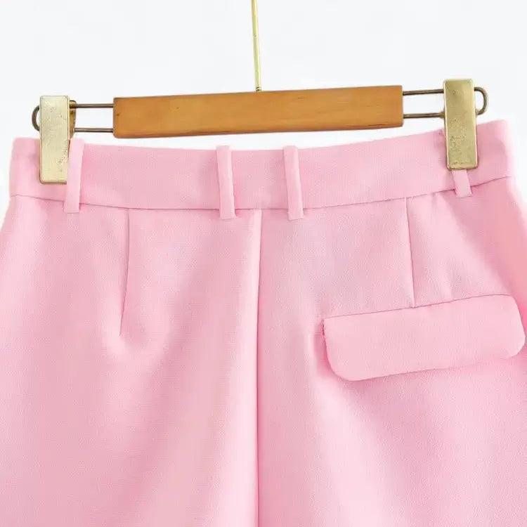 Vista traseira do short alfaiataria feminino rosa, de cintura alta, com presilhas de cinto e detalhe de bolso com aba na parte posterior.