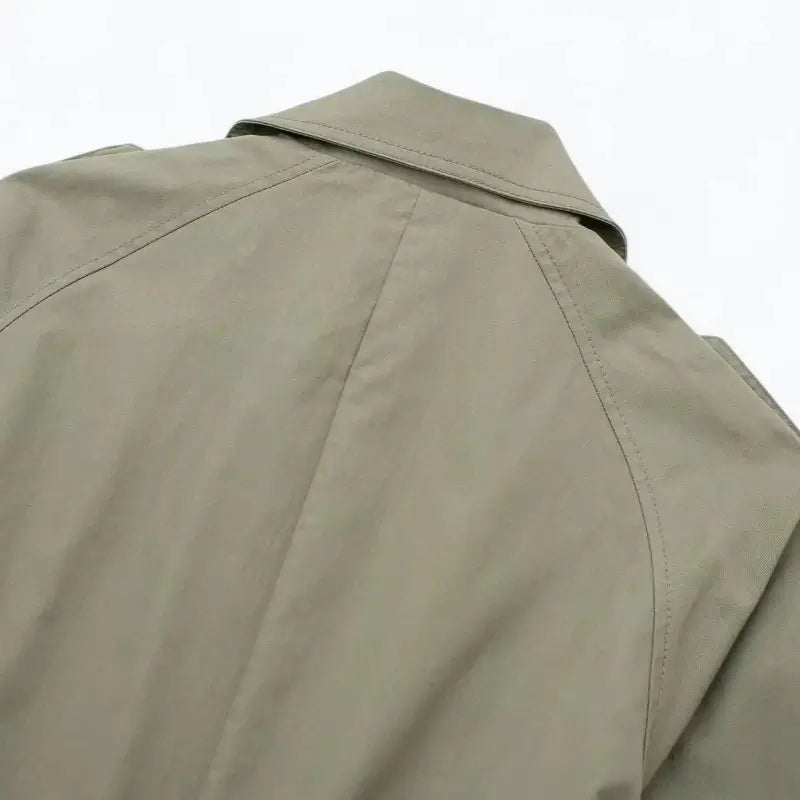 Close-up da gola e parte superior das costas do sobretudo feminino bege estilo trench coat, exibindo as costuras.