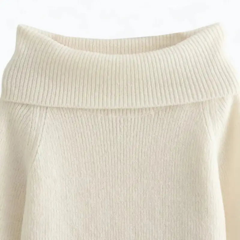 Close-up do suéter feminino off white, evidenciando o decote ombro a ombro e a textura canelada.