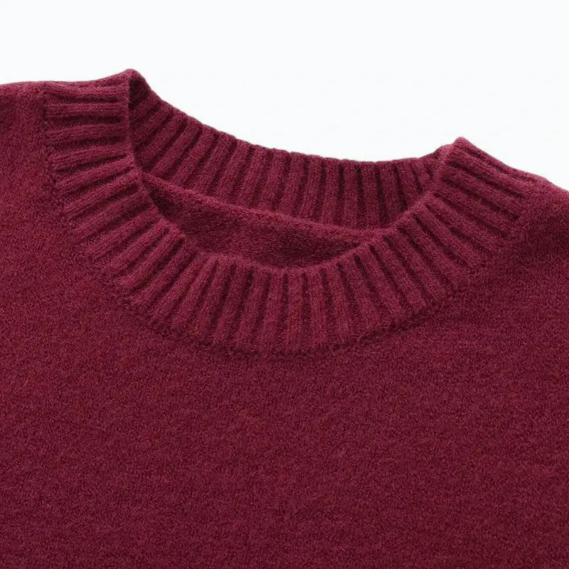 Close-up da gola redonda canelada do suéter feminino vermelho, destacando a textura felpuda da peça.