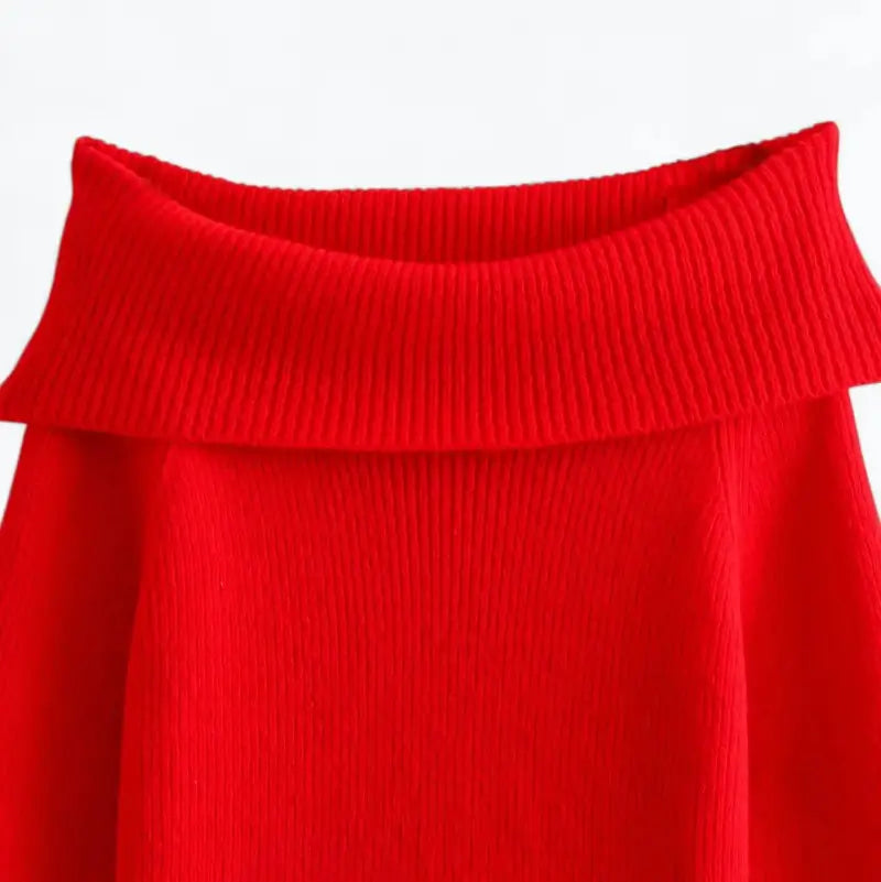 Close-up do suéter feminino vermelho, evidenciando o decote ombro a ombro e a textura canelada.